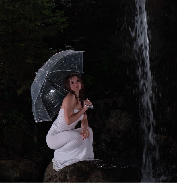 Model mit transparentem Schirm vor einem Wasserfall